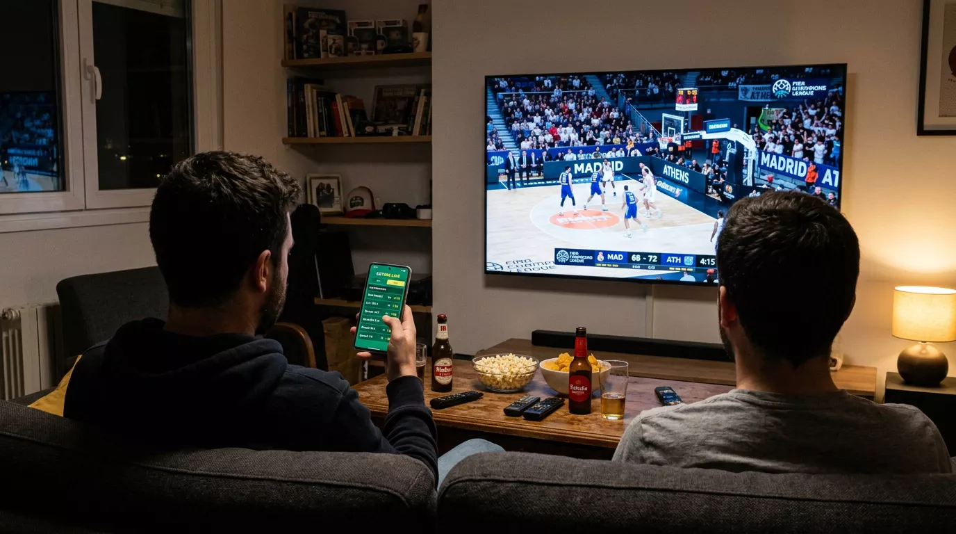 Aficionados viendo un partido de baloncesto de la Liga Endesa en directo mientras consultan cuotas en el móvil